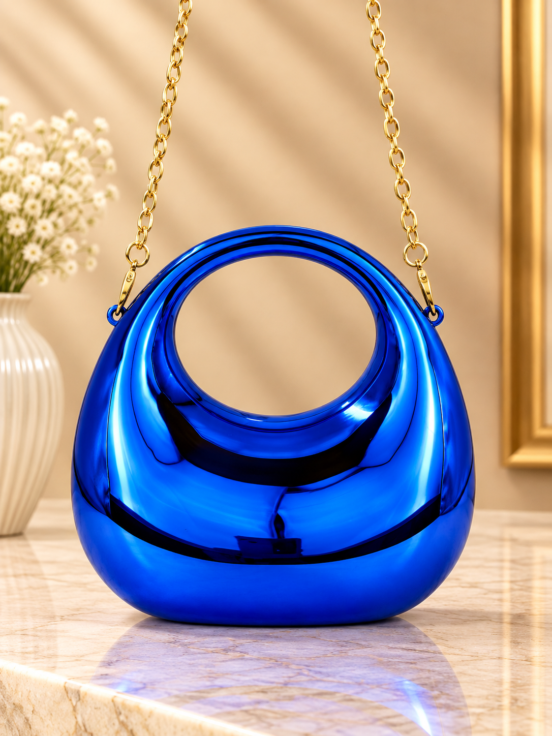 Blue metallic crescent evening handbag with glossy finish and gold chain straps